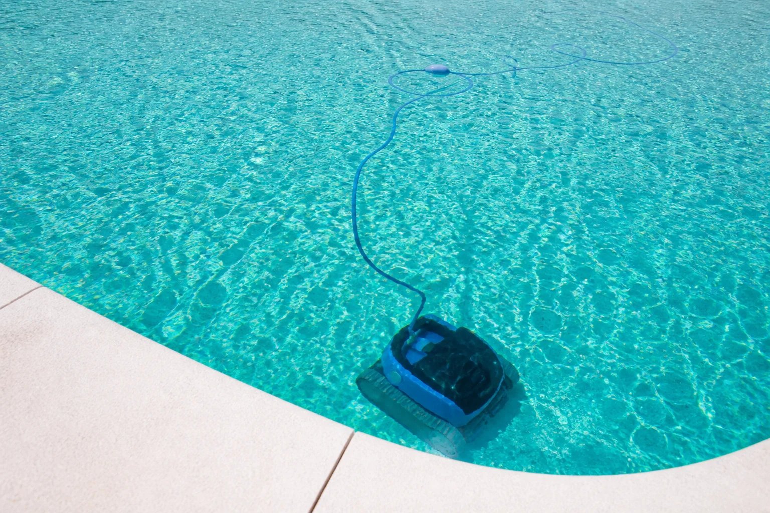 Robot limpiafondos trabajando en el fondo de una piscina cristalina